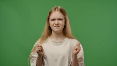 Gençlik duyguları konsepti. Genç bir kız kameraya yumruk ve beklenen yüzle poz veriyor. Bekleyen yüz ifadesi. Krom anahtar yeşil ekran arka plan modelinde izole edilmiş..