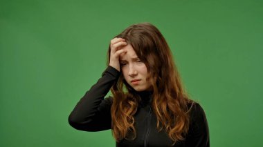 Gençlik duyguları konsepti. Genç kız kameraya poz veriyor ve ateşi var. Alnına elle dokunuyor. Yorgun bir ifade takınıyor..