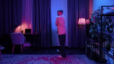 Parlak renkli ışıklandırmalı şık bir odada hip hop yapan bir adam enerjik bir atmosfer yaratıyor. Yavaş Hareket