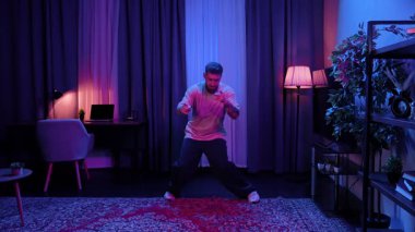 Parlak renkli ışıklandırmalı şık bir odada hip hop yapan bir adam enerjik bir atmosfer yaratıyor. Yavaş Hareket