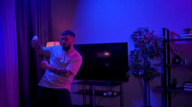 Canlı, neon ışıklı, dinamik mor ve mavi ışıklarla dolu bir odada hip hop yapan bir adam. Yavaş Hareket