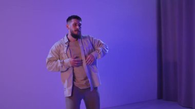 Sıradan takım elbiseli bir adam, sahnede mor ışıkla hip hop yapıyor, enerjik hareketlerini ve tarzını sergiliyor. Yavaş Hareket