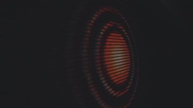 Canlı turuncu ışıkları olan bir hoparlör konisinin soyut yakın görüntüsü, ağ dokusunu ve dairesel tasarımı vurguluyor. Makro