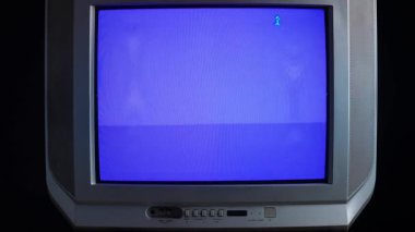 Eski bir teknolojiyi vurgulayan, köşesinde basit bir simge olan klasik bir mavi ekran gösteren bir retro CRT televizyon..