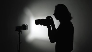 Stüdyo ışıklarıyla siluete bürünmüş bir fotoğrafçı hassas ve yetenekli bir anı yakalıyor..