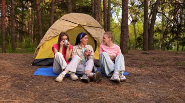 Üç arkadaş ormanda bir çadırda oturup, bir kamp gezisi sırasında içkinin ve arkadaşlığın tadını çıkarıyorlar..