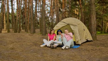 Üç arkadaş ormanda kamp yaparken heyecan verici bir an yaşadılar, bir çadırın etrafında toplandılar..