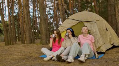 Üç arkadaş ormanda bir çadırda oturup, bir kamp gezisi sırasında içkinin ve arkadaşlığın tadını çıkarıyorlar..