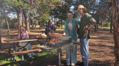 Bir grup arkadaş güneşli bir günün tadını çıkarıyorlar. Uzun ağaçlarla çevrili, pitoresk bir parkta barbekü yapıyorlar. Yavaş çekim