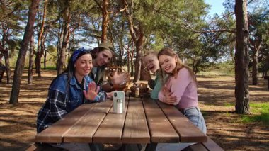 Bir grup arkadaş, orman ortamında piknikte harika vakit geçiriyorlar. Anları yakalamak için telefon kullanıyorlar..