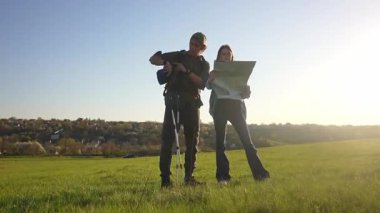 Bir çift yürüyüşçü, açık hava maceralarına hazırlanmak için uçsuz bucaksız yeşil bir alanda haritaya danışıyor. Yavaş çekim