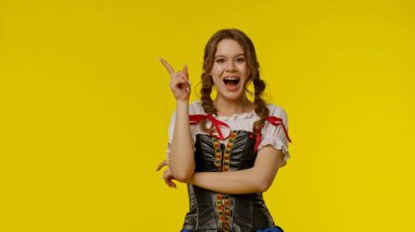 Geleneksel giyinmiş genç bir kadın neşeli bir şekilde gülümser ve canlı sarı bir zemin üzerinde hareketlerle mutluluğu yakalar..