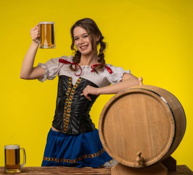 Geleneksel Dirndl elbisesi giymiş neşeli bir kadın elinde bir bira bardağı ile Ekim Festivali 'nin ruhunu kutluyor..