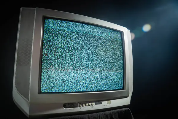 Klasik bir analog televizyon seti statik gürültüyü gösteriyor, teknolojik nostaljiyi ve estetiği vurguluyor.