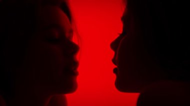 Aynadan yansıyan parlak kırmızı bir arkaplana yapışmış dilleri olan bir yüzü resmeden sanatsal bir fotoğraf. Yavaş çekim