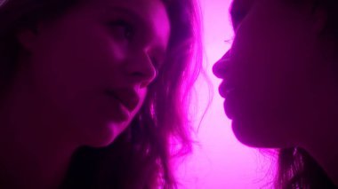 Yumuşak mor bir ışıkla aydınlatılmış aynaya bakan bir kadının yansımasını tasvir eden samimi bir sahne..