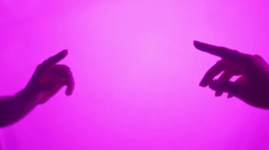 İki el neredeyse birbirine dokunuyor, canlı mor bir arkaplan karşısında bir bağ ve duygu duygusu yaratıyor. Yavaş çekim