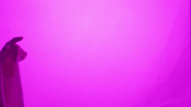 İki el birbirine doğru uzanıyor, canlı mor bir arkaplana karşı siluet, bir bağlantı ve beklenti hissi yaratıyor. Yavaş çekim