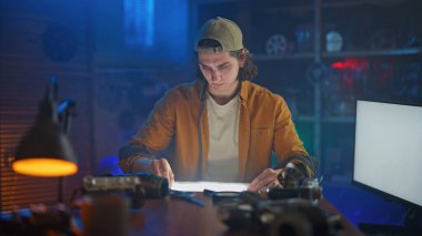 Bir atölyede genç bir adam, çeşitli alet ve ekipmanlarla çevrili projesine konsantre oluyor..