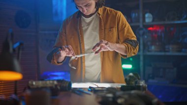 Genç bir zanaatkar, loş aydınlatılmış bir atölyede özenle yenilikçi tasarımlar yaratıyor..