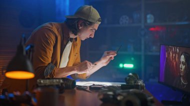 Bir adam dikkatle film görüntülerini montajlıyor. Etrafı donanımlarla çevrili..