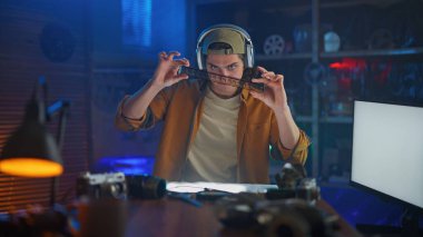 Mühendislik atölyesindeki genç bir adam çeşitli teknik aletler kullanır. Sahne odaklanma ve hassasiyeti iletir..