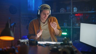 Kulaklık takan genç bir adam teknoloji esinlenilmiş bir stüdyoda bir masada otururken müzik dinliyor. Oda mavi ve yeşil ışıklarla aydınlanıyor. Yaratıcı atmosferi arttırıyor..