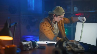 Çeşitli fotoğraf ekipmanları ve ışıklandırma ile karanlık bir odada film çeken kişi, film geliştirmenin titiz sürecini gözler önüne seriyor..