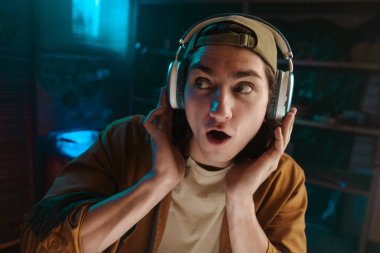 Kulaklık takan genç bir adam müzik dinlerken gözle görülür şekilde şaşırır. Şaşırmış ve meşgul görünüyor. Güçlü bir ses deneyimi olduğunu gösteriyor..