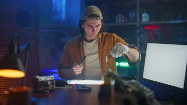 Laboratuvarda genç bir müfettiş, eski fotoğraf ekipmanlarıyla çevrili bir büyüteçle bir film şeridini yakından inceliyor..