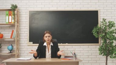 Okul öğretmeni sınıfta öğrencilere konuşuyor. Sınav kağıtlarını masadan kaldırıp öğrencilere kızgın bir şekilde konuşan genç bir üniversite öğretmeni. Eğitim kavramı