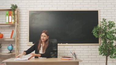 Okul öğretmeni sınıfta öğrencilere konuşuyor. Sınav kağıtlarını masadan kaldırıp öğrencilere kızgın bir şekilde konuşan genç bir üniversite öğretmeni. Eğitim kavramı