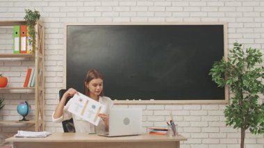 Okul öğretmeni sınıfta öğrencilere konuşuyor. Sınıftaki masada oturan genç bayan kolej öğretmeni çocuklara bilgisayar kullanarak astronomi dersini açıklıyor. Eğitim kavramı.