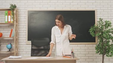 Okul öğretmeni sınıfta öğrencilere konuşuyor. Genç bayan üniversite öğretmeni sınıfa giriyor ve sınıfın önünde ayakta duruyor. Öğrencilere dersi açıklıyor. Eğitim kavramı.