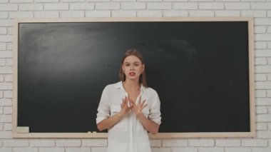 Okul öğretmeni sınıfta öğrencilere konuşuyor. Sınıftaki genç bayan üniversite öğretmeni tahtaya çıkıp öğrencilere dersi açıklıyor. Eğitim kavramı.