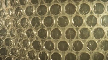 Baloncuklu ambalaj ambalajının detaylı bir yakın çekimi benzersiz dokusunu ve desenini gösterir, genellikle ambalaj ve stres giderme için kullanılır. Macro, ağır çekim.