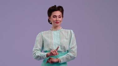 Mor stüdyo arka planında çekici saç stili pozları olan klasik kıyafetli genç bir kadın. Eski moda modunda güzel bir aktris parmağını yana doğru gösteriyor. Güzellik ve eski tarz konsept.