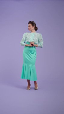 Klasik kıyafetli, çekici saç stili olan genç bir kadın mor stüdyo geçmişinde poz veriyor. Retro tarzında güzel bir aktris göz kırpıyor ve kamerayı işaret ediyor. Güzellik ve eski tarz konsept.