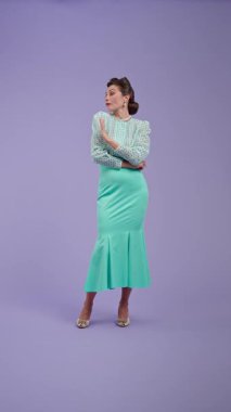 Klasik kıyafetli, çekici saç stili olan genç bir kadın mor stüdyo geçmişinde poz veriyor. Retro tarzında güzel bir aktris hoşnutsuzluk duygusunu ifade eder. Güzellik ve eski tarz konsept.