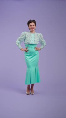 Klasik kıyafetli, çekici saç stili olan genç bir kadın mor stüdyo geçmişinde poz veriyor. Retro tarzında güzel bir aktris kameraya mutlu bir şekilde gülümser. Güzellik ve eski tarz konsept.