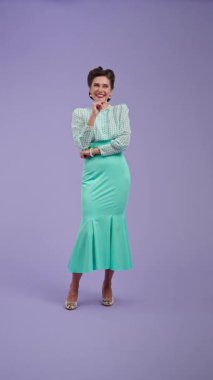 Klasik kıyafetli, çekici saç stili olan genç bir kadın mor stüdyo geçmişinde poz veriyor. Retro tarzında güzel bir aktris samimi mutluluğu ifade ederek gülüyor. Güzellik ve eski tarz konsept.