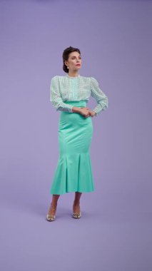 Klasik kıyafetli, çekici saç stili olan genç bir kadın mor stüdyo geçmişinde poz veriyor. Retro tarzında güzel bir aktris samimi mutluluğu ifade ederek gülüyor. Güzellik ve eski tarz konsept.