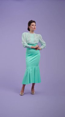 Klasik kıyafetli, çekici saç stili olan genç bir kadın mor stüdyo geçmişinde poz veriyor. Retro tarzında güzel bir aktris samimi mutluluğu ifade ederek gülüyor. Güzellik ve eski tarz konsept.