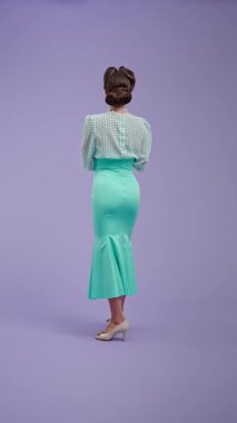 Mor stüdyo arka planında çekici saç stili olan klasik kıyafetli genç bir kadın. Retro tarzında güzel bir aktris elinde spreyle kameraya döner. Güzellik ve eski tarz konsept.