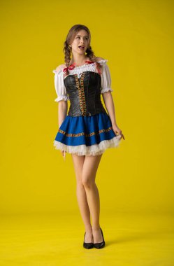 Geleneksel folklorik giyinmiş bir kadın canlı sarı bir arka plana karşı poz verir, kültürel çekiciliği ve zarafeti somutlaştırır..