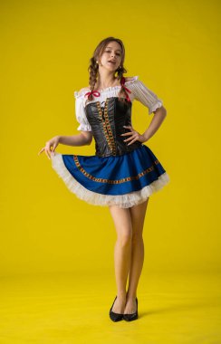 Geleneksel folklorik giyinmiş bir kadın canlı sarı bir arka plana karşı poz verir, kültürel çekiciliği ve zarafeti somutlaştırır..