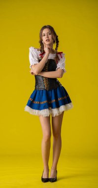 Geleneksel folklorik giyinmiş bir kadın canlı sarı bir arka plana karşı poz verir, kültürel çekiciliği ve zarafeti somutlaştırır..