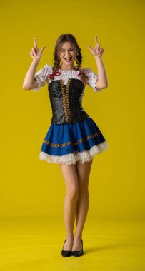 Genç bir kadın geleneksel bir Bavyera elbisesiyle neşeli bir şekilde poz veriyor..