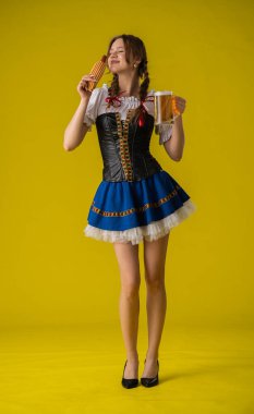 Bavyera kıyafetli bir kadın, geleneksel Bavyera şenliklerini sembolize ederek simgeleyen simit ve bira içiyor..