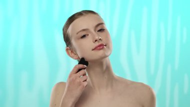Genç bir kadın cildinde yüz masajı aleti kullanıyor. Cilt bakımının önemini vurguluyor..
